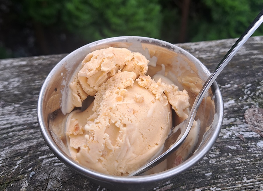 A tiny metal cup with pink ice cream and a spoon